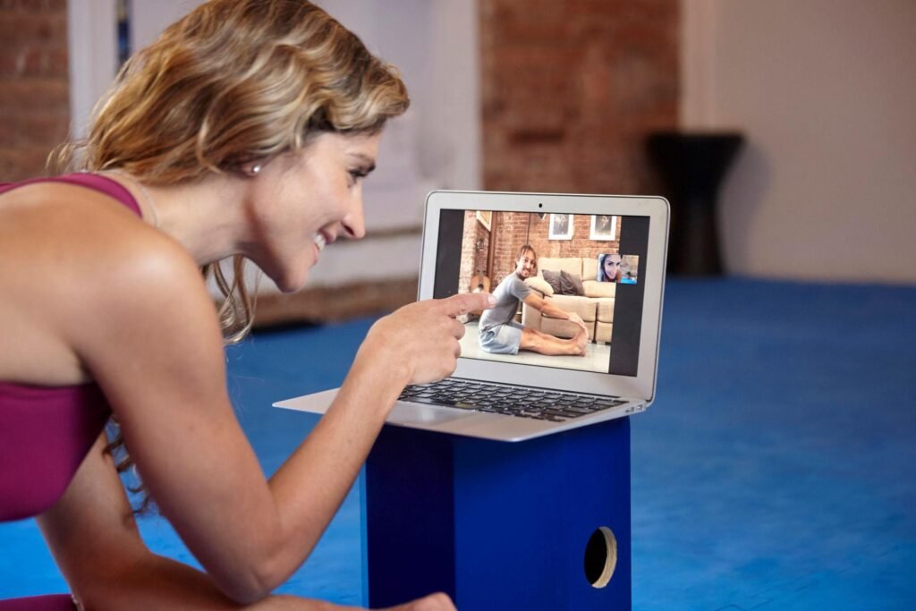 woman attending online yoga class on laptop with instructor